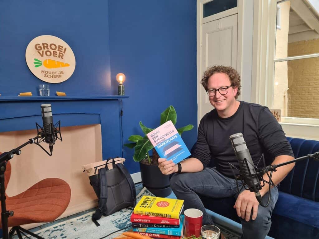 Wout Withagen in de Groeivoer Podcast studio met het boek '"Bouw een Succesvolle Online Marktplaats" in zijn hand